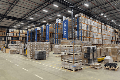 Loods met pallets en heftrucks langs een rijbaan met op de achtergrond stellingen