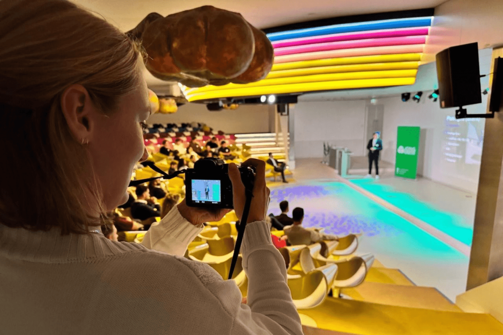 Fotograaf maakt foto van spreker op podium in felgekleurde ruimte