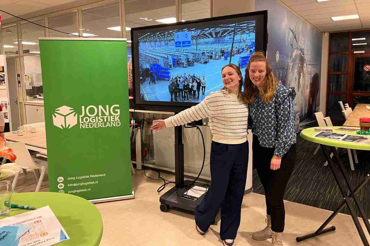 Twee mensen voor een digitaal scherm met een groene banner op open dag windesheim