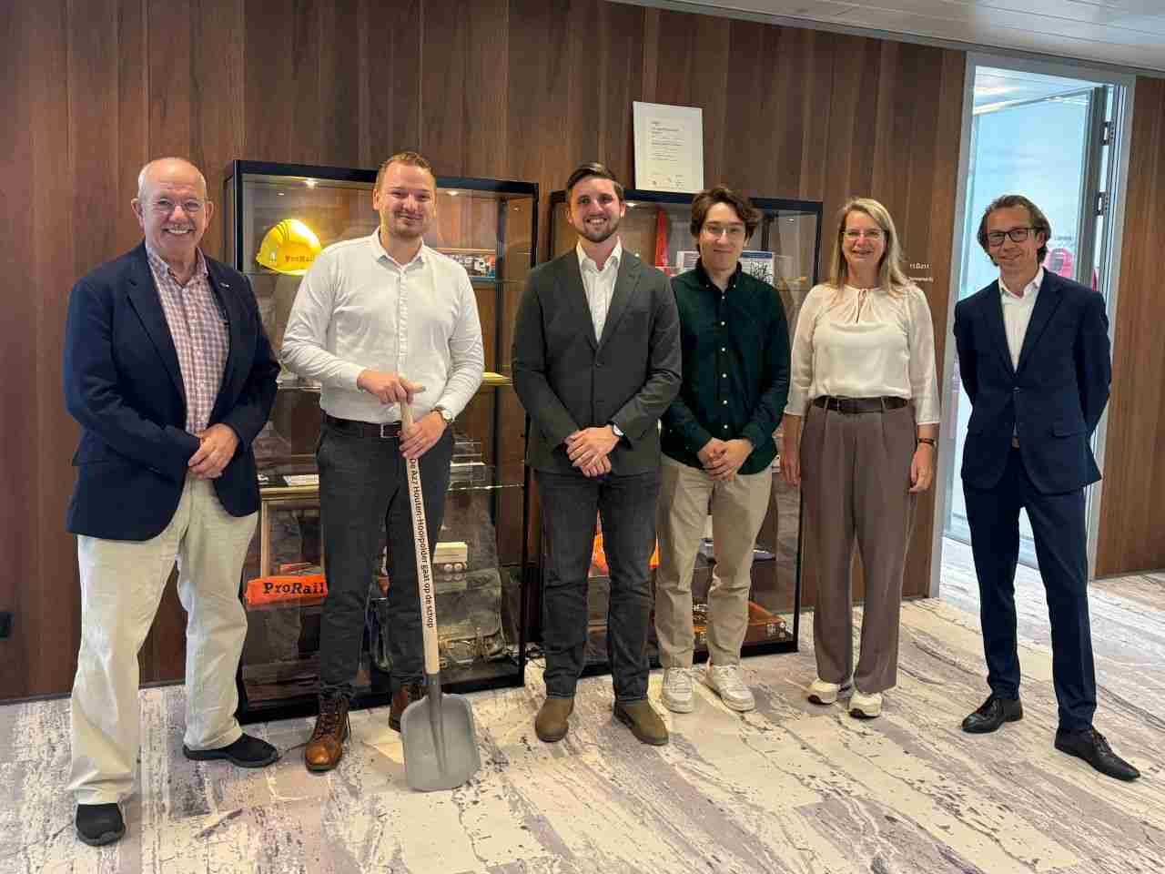 Een groep mensen poseert voor een vitrinekast bij het Ministerie van Infrastructuur en Waterstaat